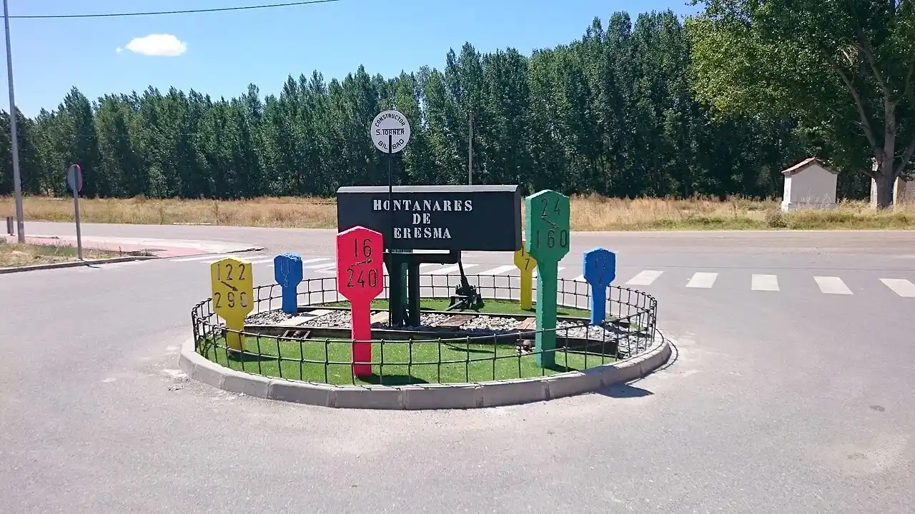 Mudanzas en Hontanares de Eresma 8 Mudanzas en Hontanares de Eresma: rotonda de entrada con el cartel del pueblo y postes ferroviarios de colores